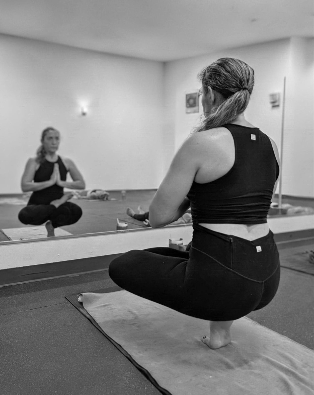 Lava Yoga Lawrence studio Student in a balanced squat facing the studio mirror at Lava Yoga Lawrence